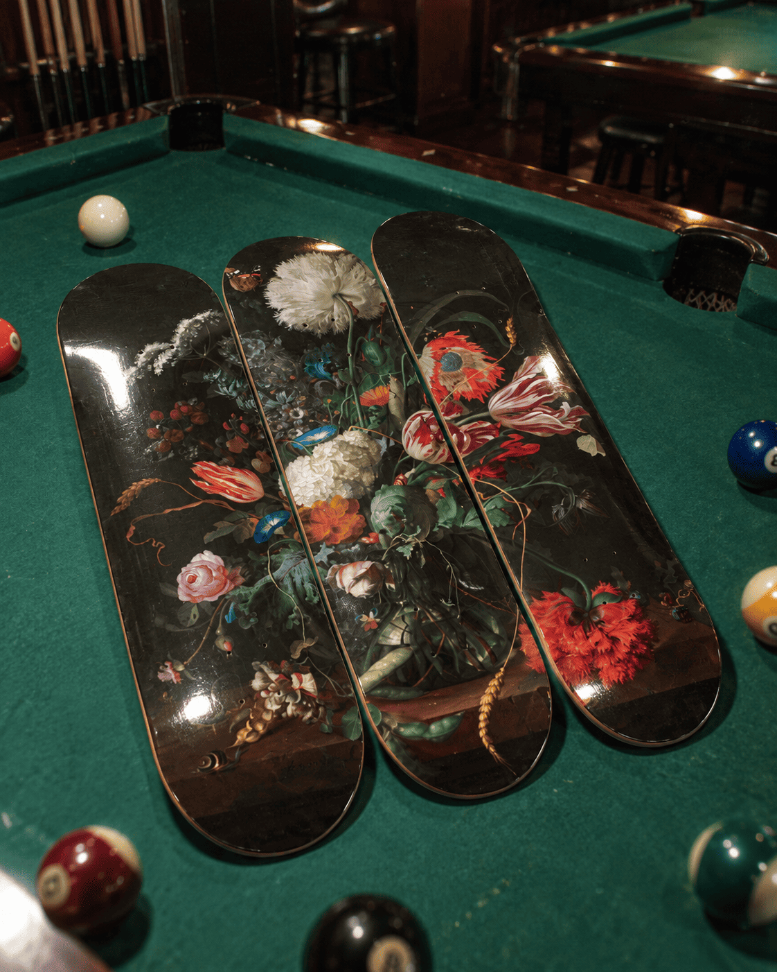 Three decorative skateboard decks forming a Jan Davidsz de Heem Baroque floral still-life triptych, laid flat on green pool-table felt with billiard balls