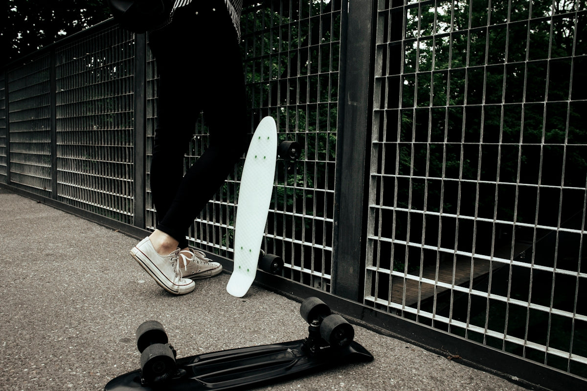 person standing near in front fence near penny board