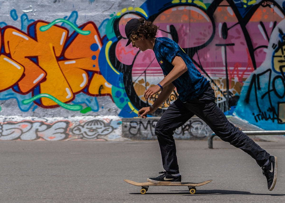 man in blue t-shirt and black denim jeans riding skateboard during daytime
