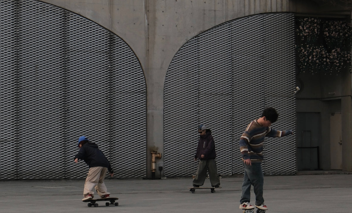 Three people skateboard near a large metal structure.