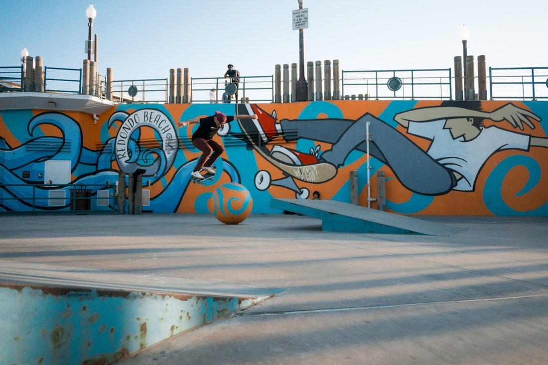 Skateboarder performs trick against colorful mural